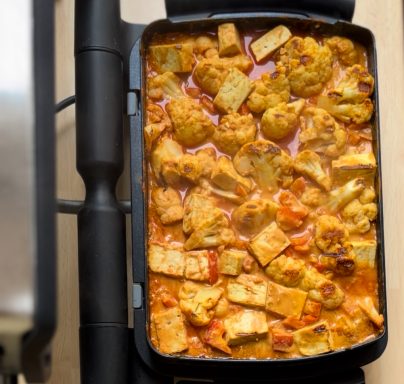 Eintopf mit Blumenkohl und Tofu in einer Pfanne, in Tomatensauce gekocht.