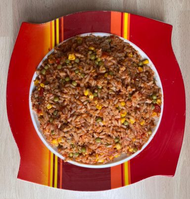 Regelmäßiger Reis mit Gemüse auf einem bunten Teller.