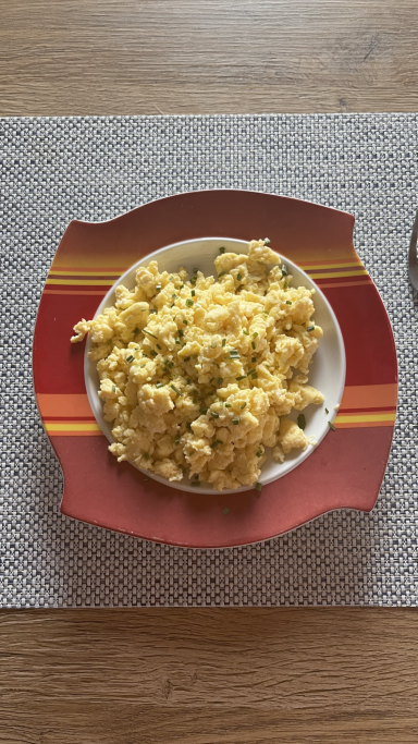 Ein Teller mit gelbem Reis und Gemüse, serviert auf einer roten Unterlage.